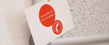 Das Foto zeigt einen Flyer mit dem Aufdruck "Anlaufstellen in Krisensituationen"