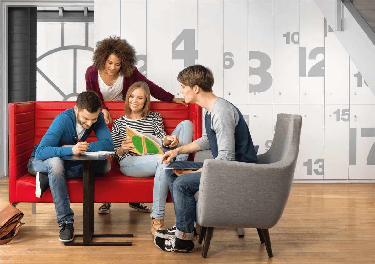 Studierende sitzen zusammen auf einer roten Couch und arbeiten gemeinsam an einer Projetkidee.